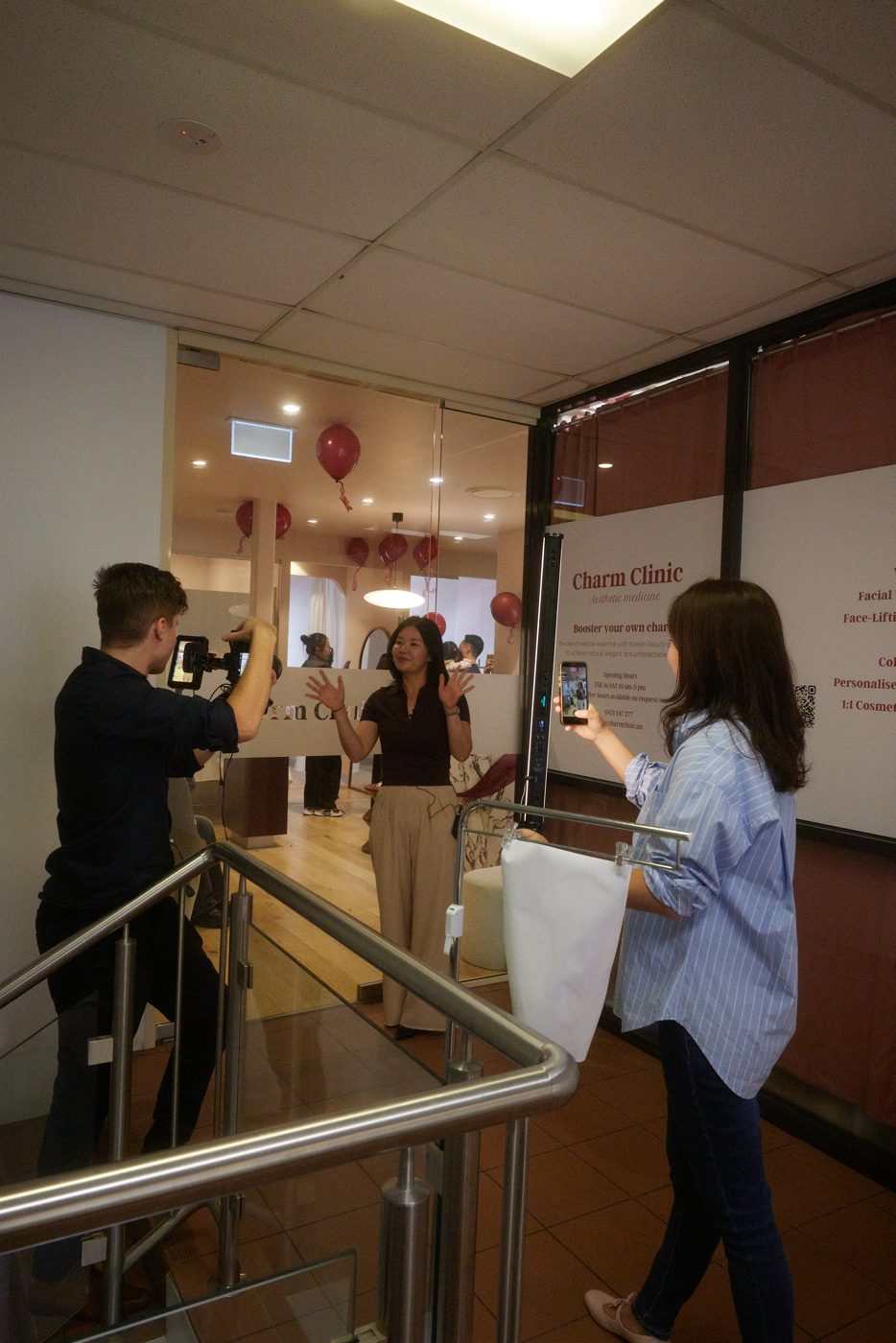 Angela filming a client on her phone inside a Sydney clinic